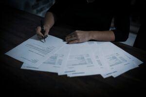 Person reviewing an insurance declaration page beside a calculator, house keys, and policy documents on a desk.