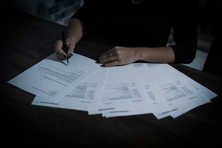 Person reviewing an insurance declaration page beside a calculator, house keys, and policy documents on a desk.